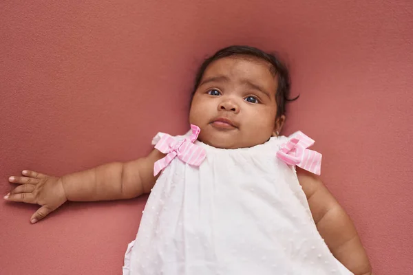 非洲裔美国婴儿躺在床上 在孤立的红色背景下 满脸轻松的表情 — 图库照片