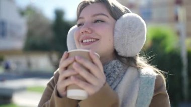 Young blonde woman smiling confident drinking coffee at street