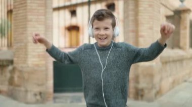 Blond child smiling confident listening to music and dancing at street