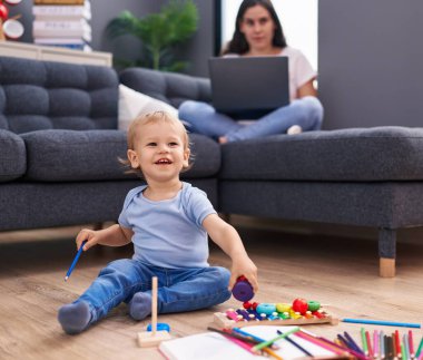 Anne ve oğlu evde oynarken dizüstü bilgisayar kullanıyor.