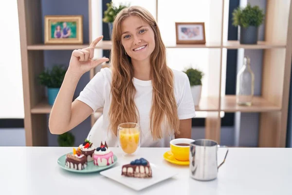 Young Caucasian Woman Eating Pastries Breakfast Smiling Confident Gesturing Hand — Stockfoto