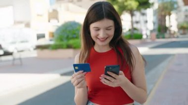 Young caucasian woman using smartphone and credit card at park