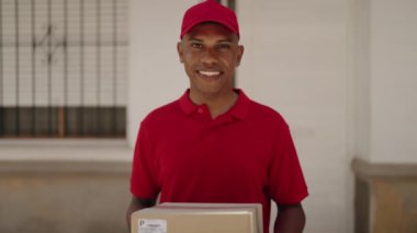 Genç Latin bir teslimatçı sokakta paket tutuyor.