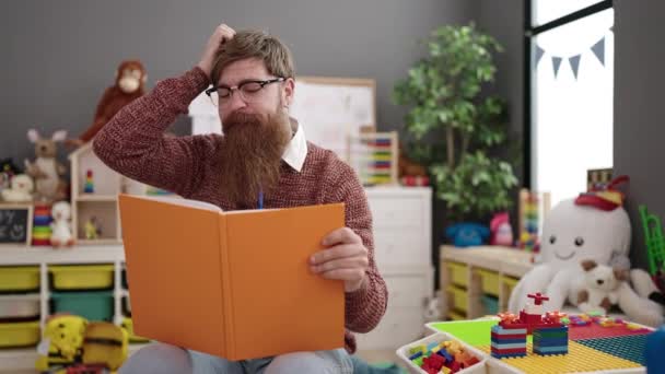 Young Redhead Man Preschool Teacher Reading Book Sitting Chair Kindergarten — Stockvideo