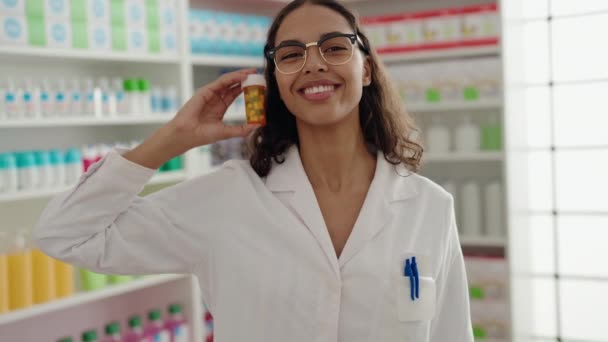 若いアフリカ系アメリカ人女性薬剤師笑顔自信を持って保持薬瓶に薬局 — ストック動画