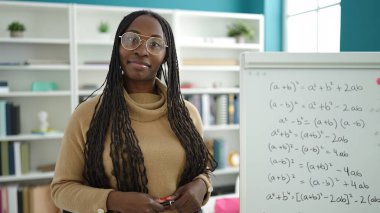 African woman smiling confident by maths magnetic board at library university