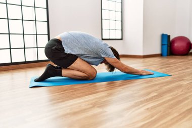 Orta yaşlı, beyaz bir adam spor merkezinde esniyor.