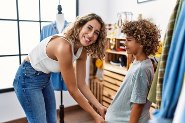 Mother and son smiling confident choosing clothes at clothing store