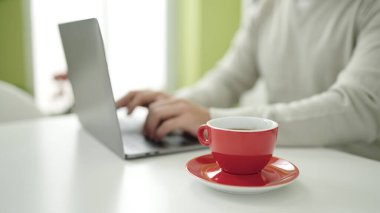 Evdeki masada dizüstü bilgisayar kullanan genç bir İspanyol.