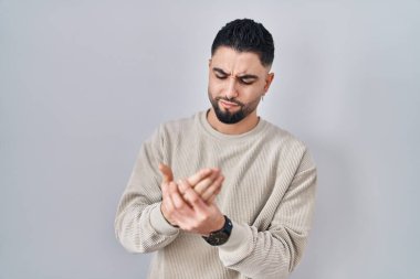 Young handsome man standing over isolated background suffering pain on hands and fingers, arthritis inflammation 