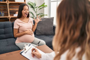 Young pregnant woman at therapy session celebrating victory with happy smile and winner expression with raised hands 