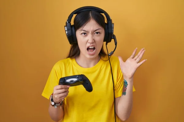 中国年轻女子疯狂地玩电子游戏 手持控制器 疯狂地大喊大叫 带着咄咄逼人的表情和手臂 沮丧的概念 — 图库照片