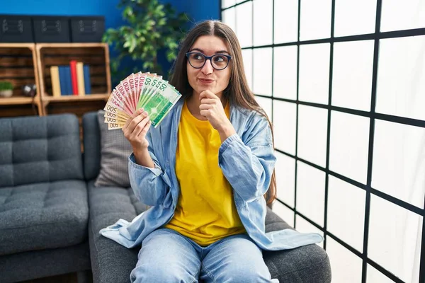 Young Hispanic Woman Holding Norwegian Banknotes Serious Face Thinking Question — Photo