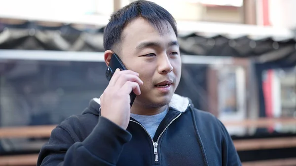 Молодой Китаец Разговаривает Смартфону Серьезным Выражением Лица Улице — стоковое фото