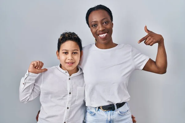 stock image Young mother and son standing together over white background looking confident with smile on face, pointing oneself with fingers proud and happy. 