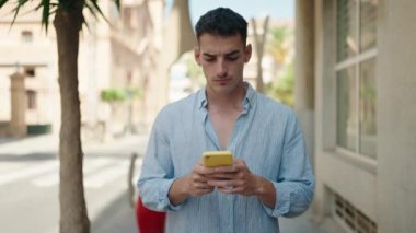 Genç İspanyol adam akıllı telefon kullanıyor. Sokakta ciddi bir ifadesi var.