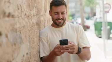 Sokakta akıllı telefon kullanan, kendine güvenen genç bir İspanyol.