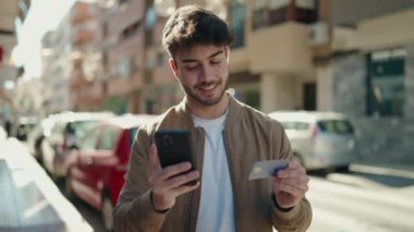 Genç İspanyol adam akıllı telefon ve kredi kartı kullanıyor.
