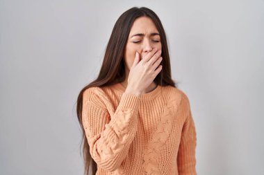 Young brunette woman standing over white background bored yawning tired covering mouth with hand. restless and sleepiness. 