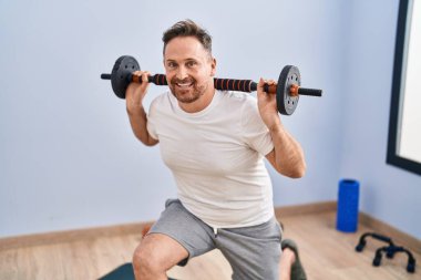 Young caucasian man smiling confident training legs exercise at sport center