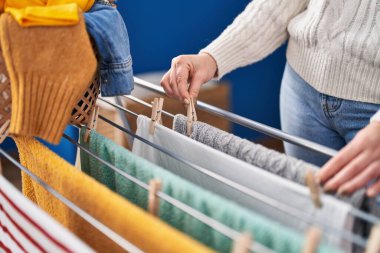 Çamaşır odasında çamaşır ipine elbise asan genç bir kadın.