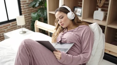 Young beautiful hispanic woman having video call lying on bed at bedroom