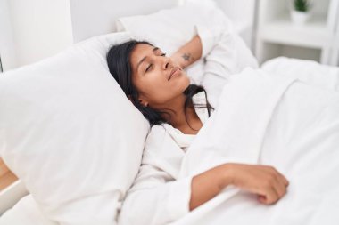 Genç, güzel, İspanyol bir kadın yatakta uzanıyor.