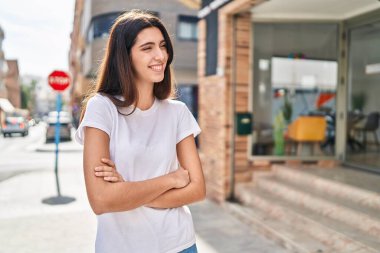 Sokakta kollarını kavuşturmuş genç, güzel İspanyol bir kadın.