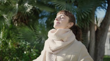 Young caucasian woman smiling confident with closed eyes enjoying sunlight at park