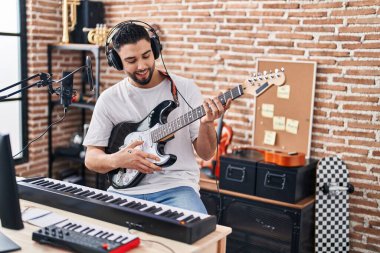 Genç Arap sanatçı müzik stüdyosunda elektro gitar çalarak şarkı söylüyor.