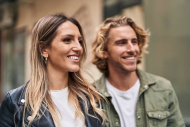 Kadın ve erkek gülümsüyor. Kendilerine güveniyorlar. Sokakta sarılıyorlar.