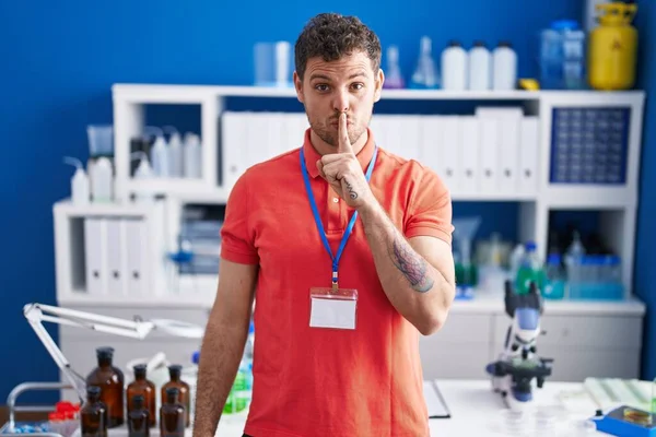 Young Hispanic Man Working Scientist Laboratory Asking Quiet Finger Lips — Stock Photo, Image
