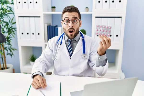 Handsome Hispanic Man Wearing Doctor Uniform Holding Prescription Pills Scared — Fotografia de Stock