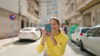 Young african american woman smiling confident using smartphone at street