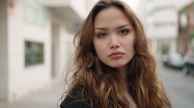 Young hispanic woman standing with relaxed expression at street