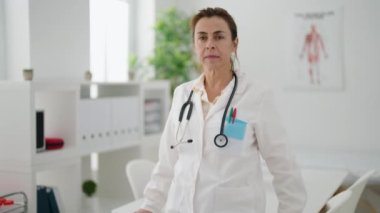 Middle age woman wearing doctor uniform standing with arms crossed gesture at clinic