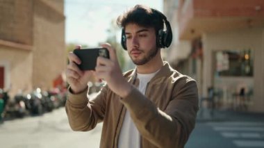 Young hispanic man smiling confident playing video game at street