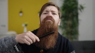 Evdeki kanepede oturan sakallı genç kızıl saçlı adam.