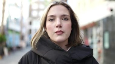 Young blonde woman standing with surprise expression at street