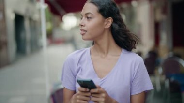 Young african american woman smiling confident using smartphone at coffee shop terrace