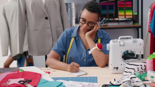 非洲裔美国妇女裁缝在裁缝店用智能手机在笔记本上写字 — 图库视频影像
