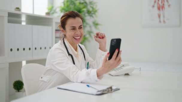 医者の制服を着た中年女性が診療所で電気通信を受けて — ストック動画