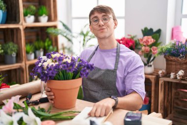 Caucasian blond man working at florist shop looking at the camera blowing a kiss on air being lovely and sexy. love expression. 