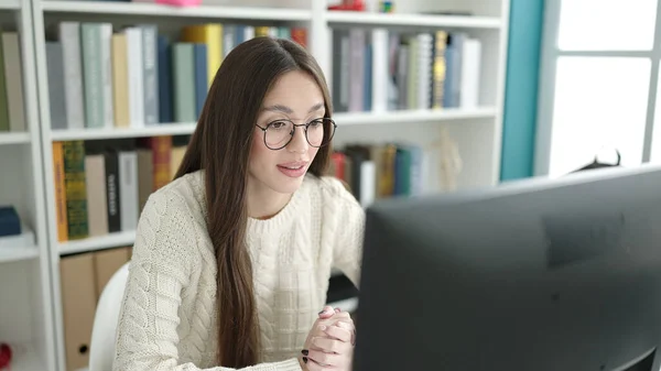 Young beautiful hispanic woman student using computer studying at library university