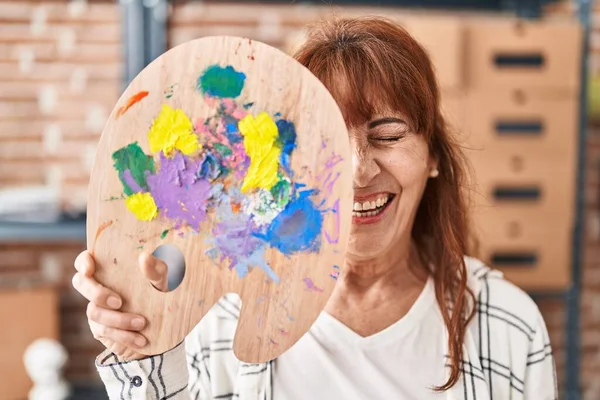 Middle Age Hispanic Woman Holding Palette Covering Face Winking Looking — Stockfoto