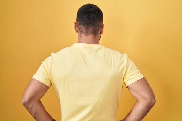Young Hispanic Man Standing Yellow Background Standing Backwards Looking Away — Φωτογραφία Αρχείου