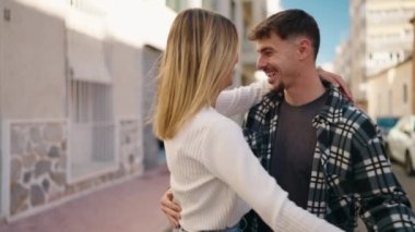 Genç çift sokakta dans ederken kendinden emin gülümsüyor