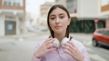 Genç İspanyol kadın sokakta müzik dinlerken kendinden emin gülümsüyor.