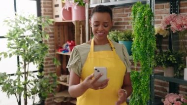 Afrikalı Amerikalı kadın çiçekçi çiçekçide akıllı telefon fabrikasıyla selfie çekiyor.