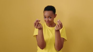 African american woman smiling confident doing spend money gesture over isolated yellow background